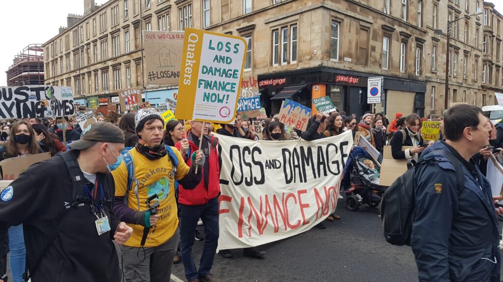 A climate justice march walks through the streets of Glasgow. Protesters carry signs calling for climate finance